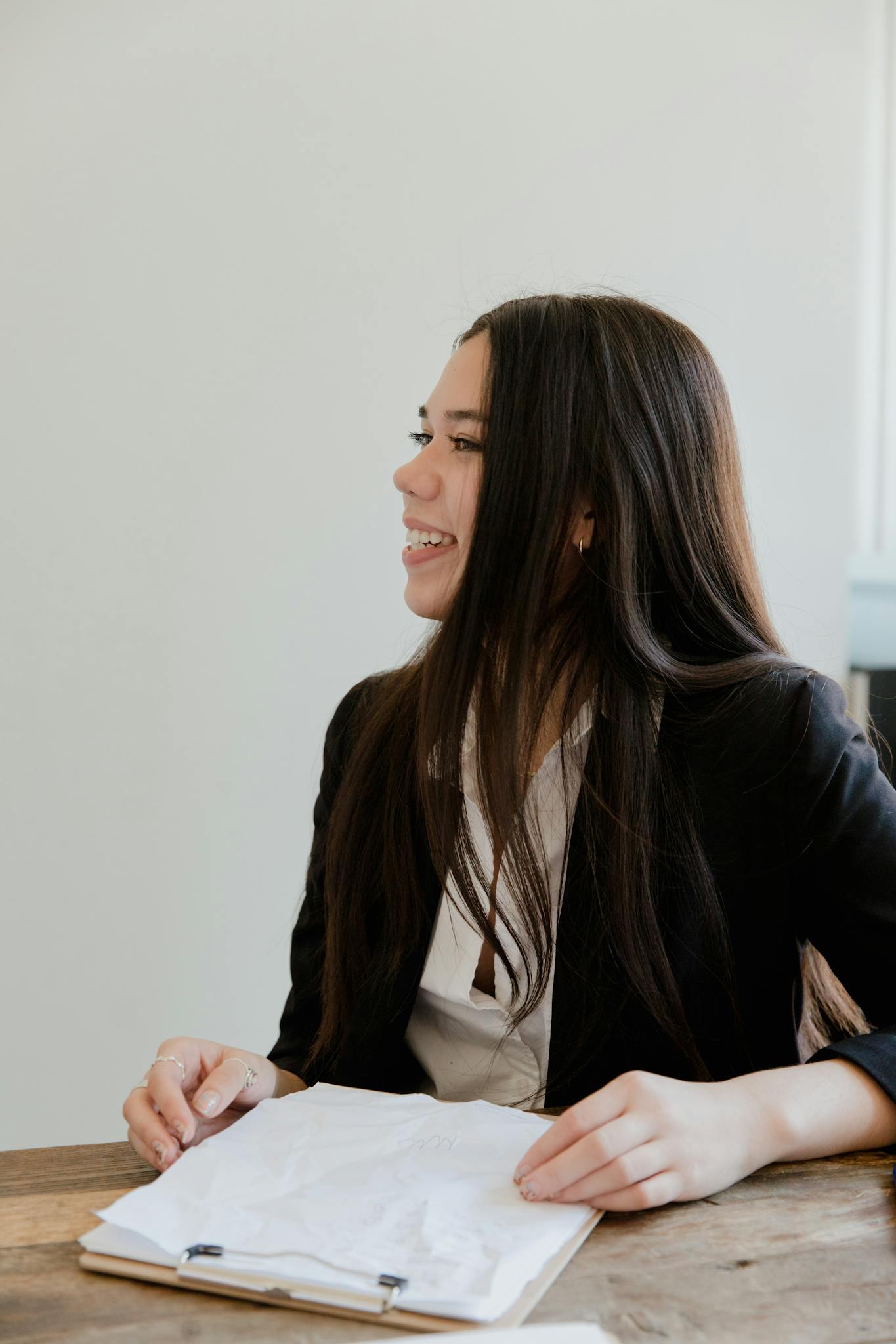Portrait of a smiling businesswoman holding papers in a bright office setting.
