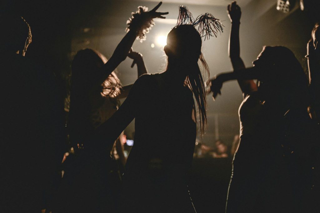 Silhouetted partygoers dancing with dynamic lighting at a lively club night.